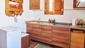 A kitchen with wooden cabinets, a granite countertop, a sink, and a refrigerator. - Rural escape with mountain views (Níjar)