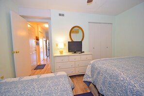 A bedroom with two beds, a dresser, a television, and a mirror. - Raffles 206-Bayside 127th St, Free WiFi, Pool, W/D, AC (Ocean City)