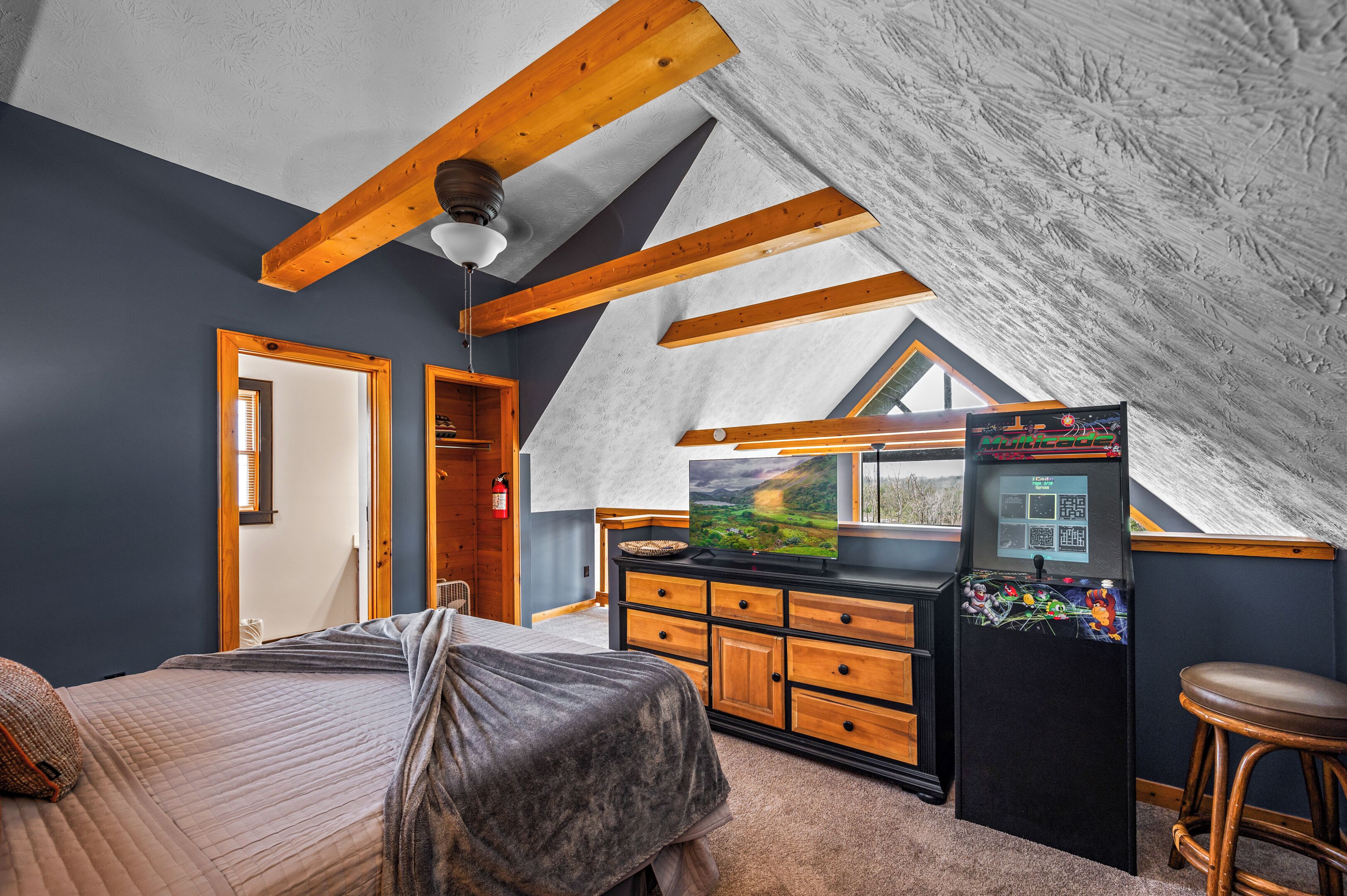 A bedroom with a bed, dresser, and a small kitchenette area with a refrigerator and microwave.