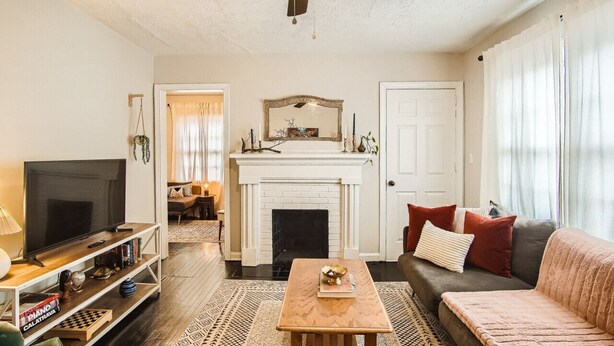 A living room with a fireplace, a television, a sofa, and a coffee table. - 1429 Lanvale · Quaint Boho Retreat Near Downtown - Pet Friendly (Atlanta)
