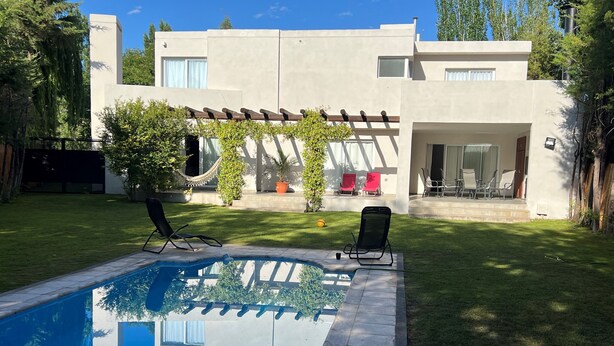 A modern house with a swimming pool, a patio with chairs, and a garden. - Mendoza House in B. Cerrado- Chacras de Coria (MENDOZA)
