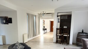 A spacious living area with a grey sofa, a wooden dining table, and a bar area with a barrel. - Mendoza House in B. Cerrado- Chacras de Coria (MENDOZA)