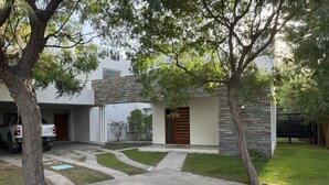 A modern house with a stone facade, a driveway, and a white car parked in the garage. - Mendoza House in B. Cerrado- Chacras de Coria (MENDOZA)