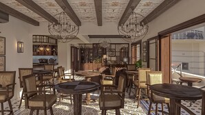 Un restaurante acogedor con mobiliario de madera, suelo estampado y un techo decorativo.