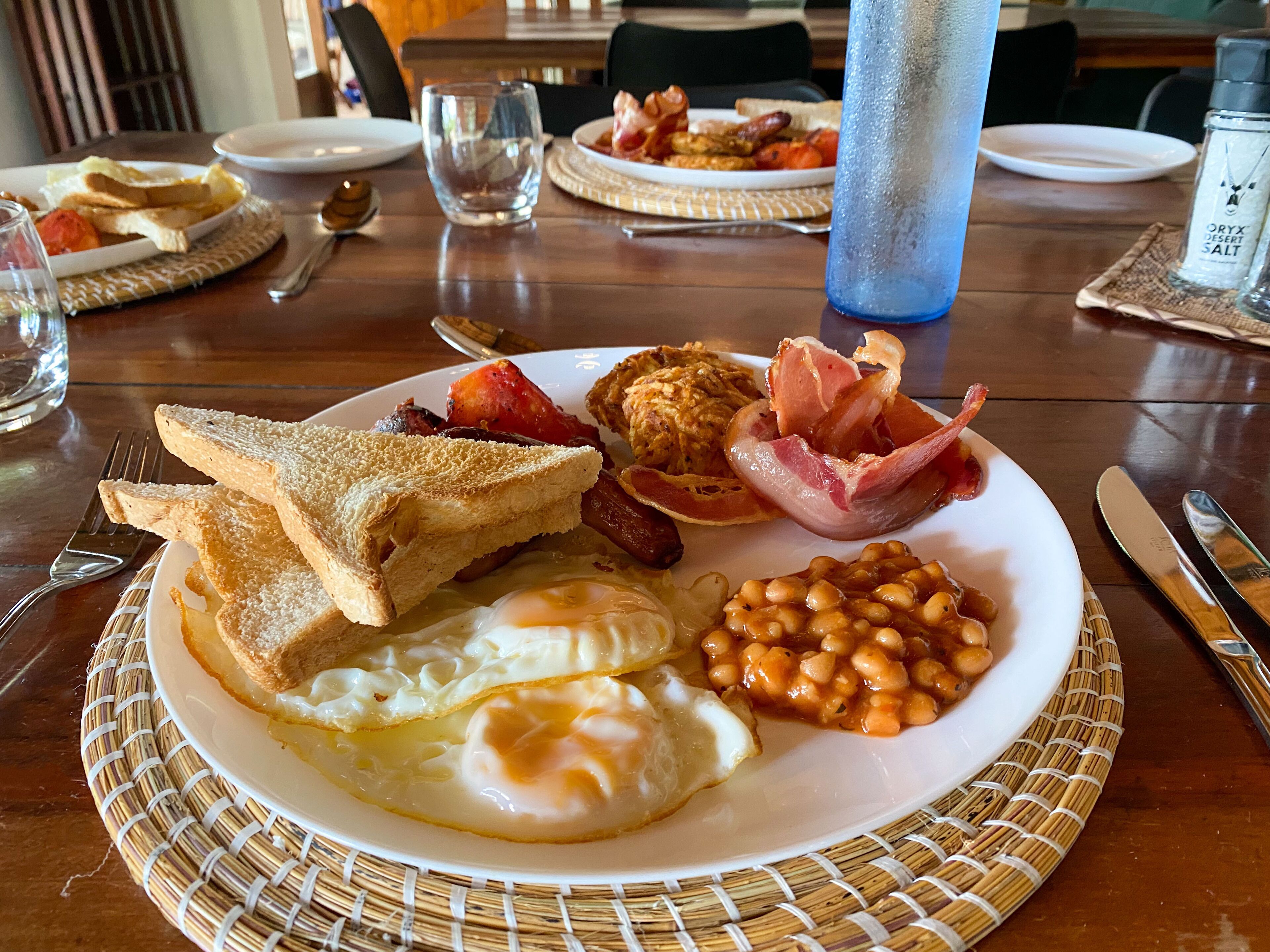 Un plato de desayuno con tostadas, huevos, tocino y frijoles.