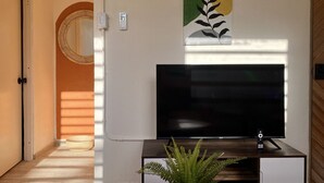 Ett modernt vardagsrum med en platt-TV, en prydnadsväxt och ett konstverk som hänger på väggen.