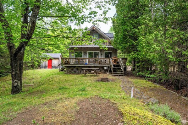 Une cabane dotée d’une terrasse, entourée d’une forêt dense.