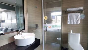 Un baño moderno con cabina de ducha de vidrio, lavamanos blanco y un inodoro.