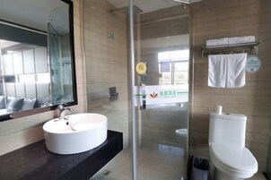 Un baño moderno con cabina de ducha de vidrio, lavamanos blanco y un inodoro.