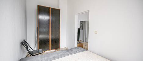 Ein Schlafzimmer mit einem Bett, einem Kleiderschrank und einem Spiegel.