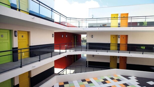 A multi-level atrium with a checkered floor, balconies, and doors in various colors. - Studio Calme et Cosy Bien Équipé (Perpignan)