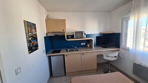 Eine kleine Küche mit Spüle, Mikrowelle und kleinem Kühlschrank.