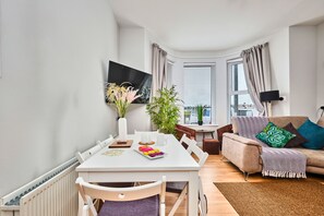 Una sala de estar moderna con comedor, un sofá y televisor.
