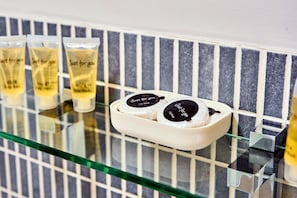 Una encimera de baño con artículos de aseo, incluyendo un jabonera y tres botellas de loción.