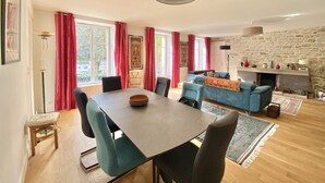 Uma sala ampla com uma mesa de jantar, cadeiras, um sofá e uma lareira.