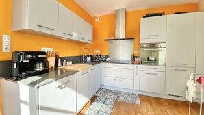 Uma cozinha moderna com armários brancos, máquina de café e fogão.