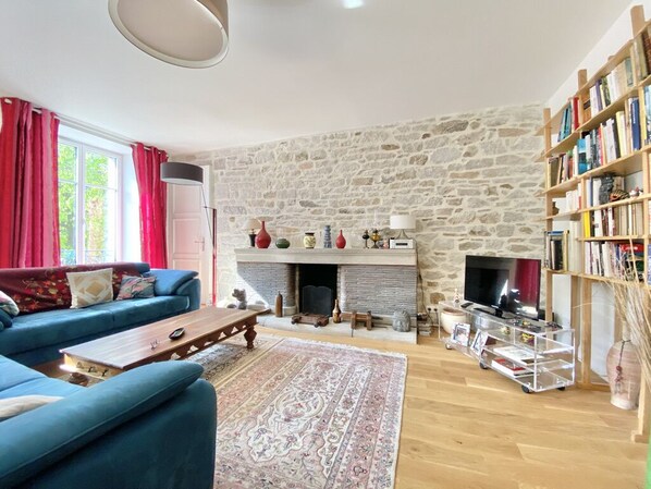 A living room with a stone wall, a fireplace, a blue sofa, a coffee table, and a bookshelf.