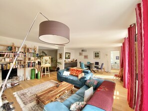 A spacious living room with a large sofa, a coffee table, and a bookshelf filled with books.