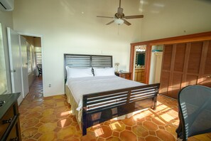 Une chambre à coucher avec un lit, un ventilateur de plafond, une armoire et une chaise.