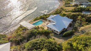 Une propriété située sur la côte, dotée d’une piscine, d’une grande maison avec un toit original et d’une vue sur l’océan.