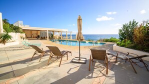 A poolside area with lounge chairs and an umbrella, overlooking a clear blue sea. - Sapala 2 - Oceanfront Poolside Apt w/ Shared Pool (Christiansted)