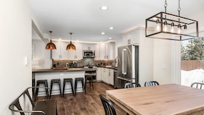 A modern kitchen with a central island, stainless steel appliances, and pendant lighting. - Luxury Duplex | Air Conditioning | Private Hot Tub | On Bus Loop (Avon)