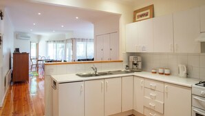 A modern kitchen with white cabinets, a stainless steel sink, and a coffee machine.