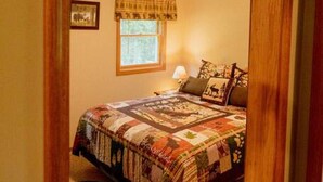Une chambre à coucher avec un lit, une table de chevet, une lampe et une fenêtre avec des rideaux.