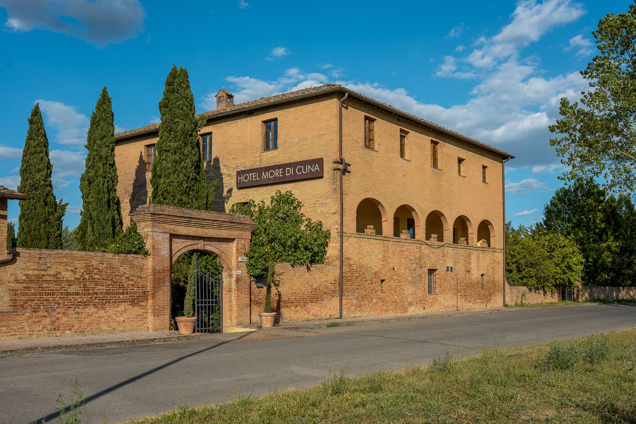 A historic building with a sign reading "HOTEL MORE DI CUNA." It features a brick facade, arched windows, and a central entrance with a gate.