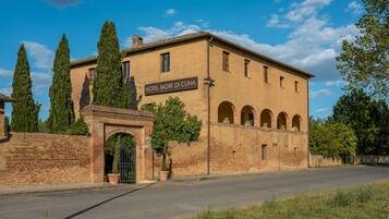 Un edificio histórico con un letrero que dice “HOTEL MORE DI CUNA”. Cuenta con fachada de ladrillo, ventanas en arco y una entrada central con portón.