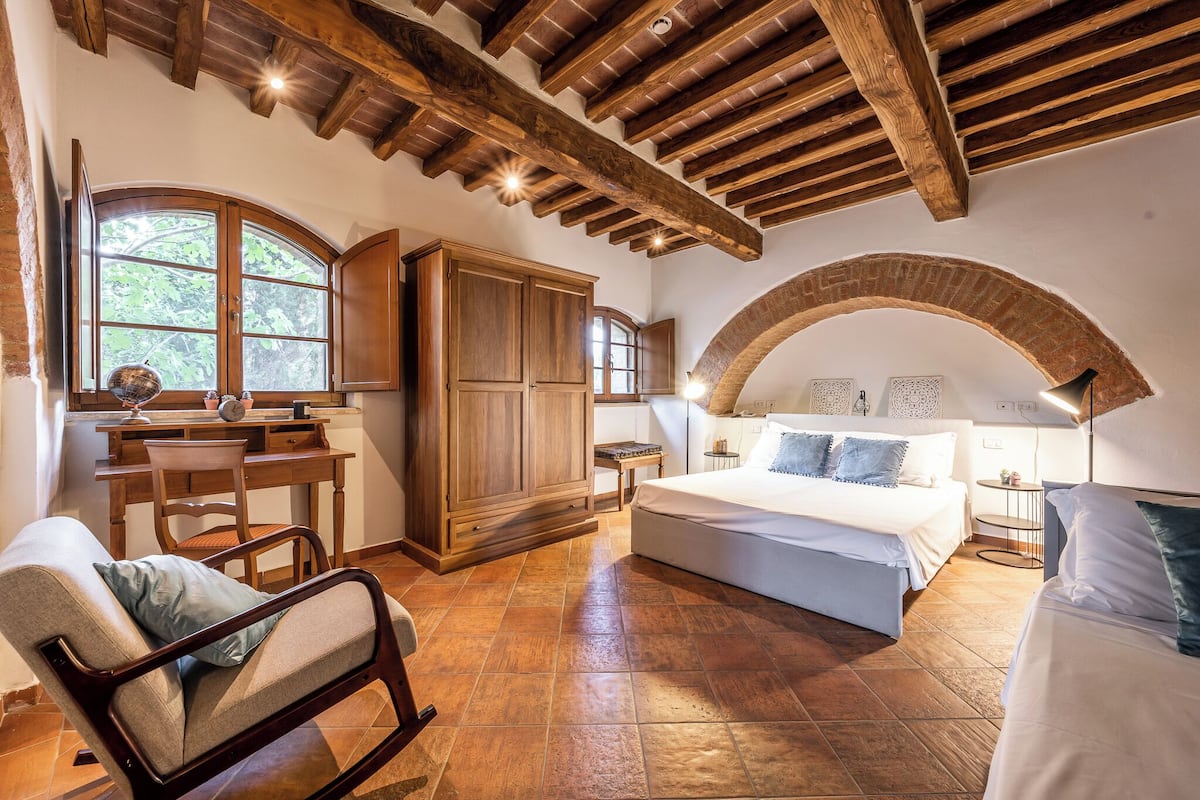 Un dormitorio con una cama grande, muebles de madera y un arco de piedra.
