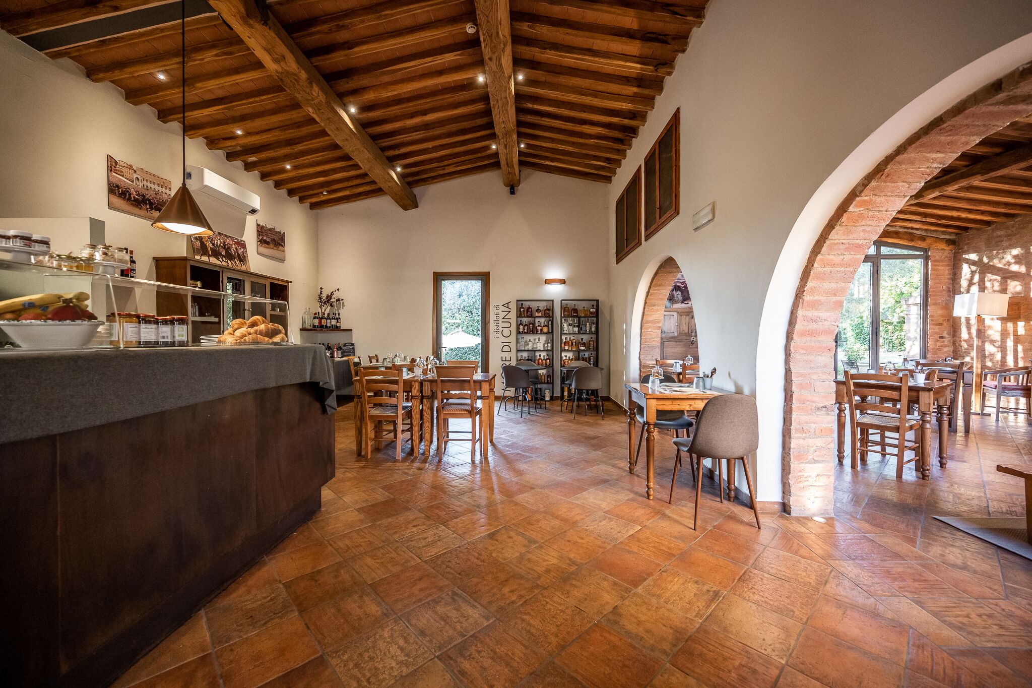 Un comedor amplio con mesas y sillas de madera, una barra con productos alimenticios y una pared de ladrillo rústica.