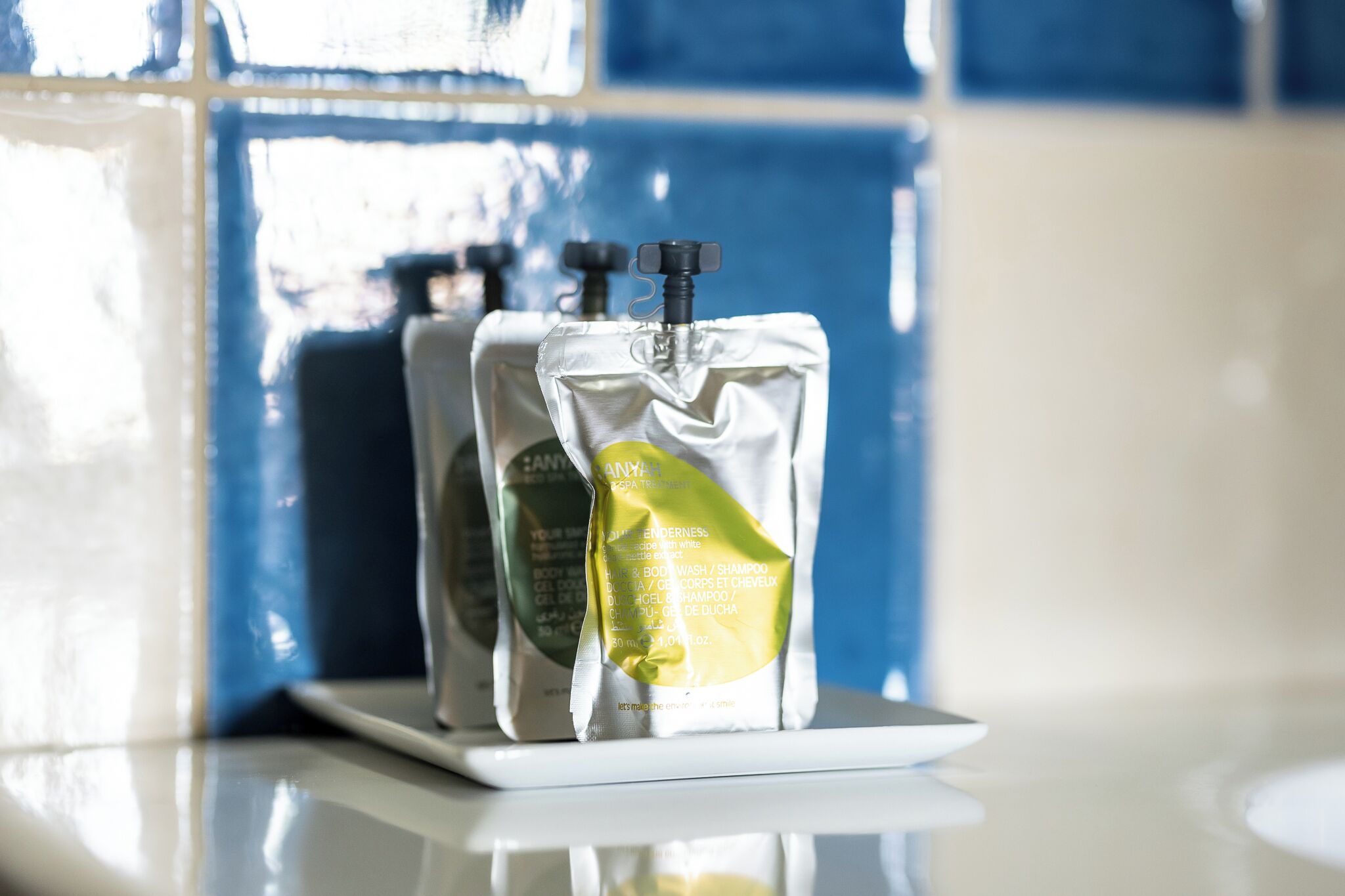 Two toiletry bags on a white tray against a blue tiled wall.