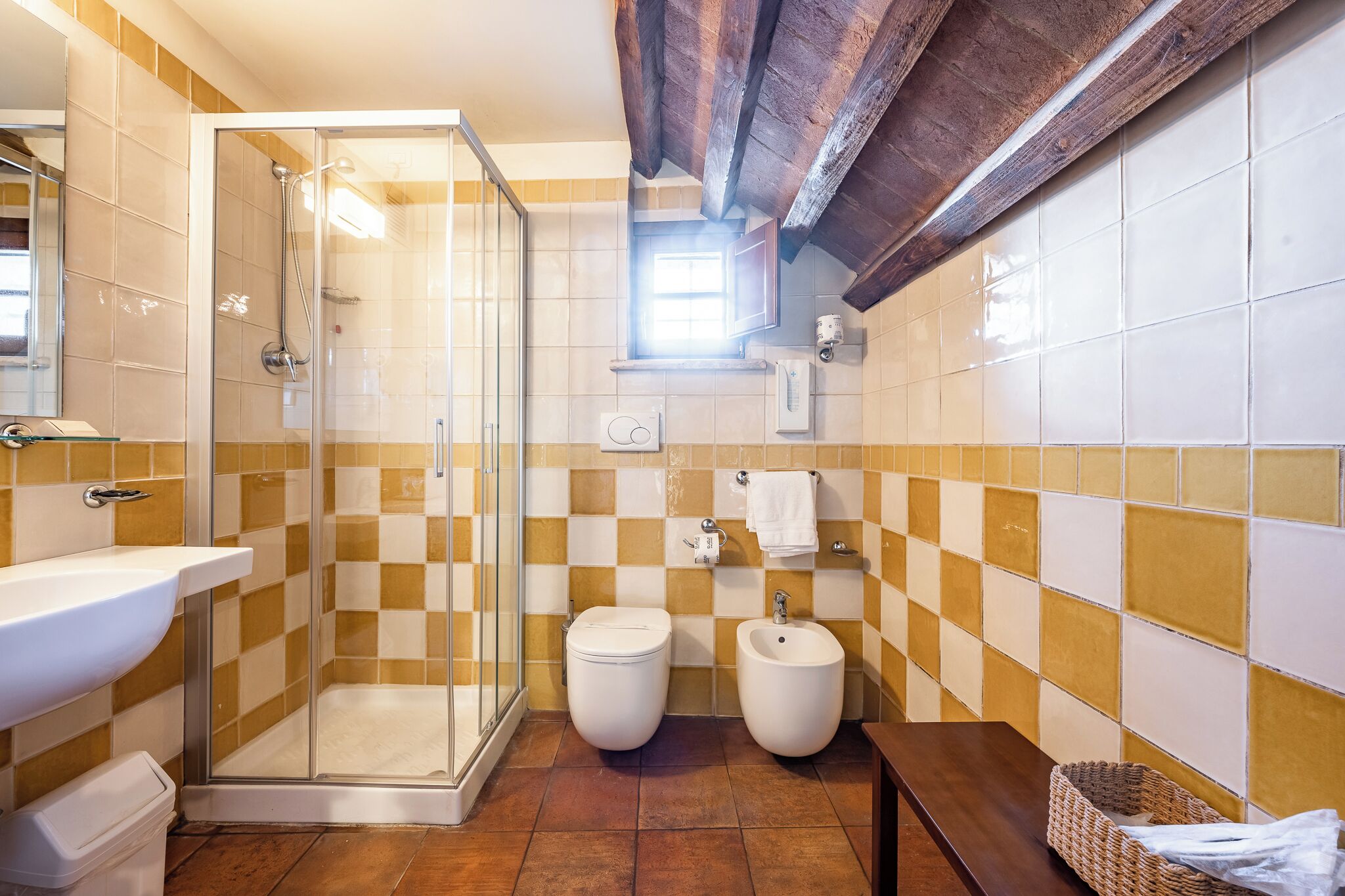 Une salle de bain avec une douche à parois de verre, un lavabo, deux toilettes et un bidet.