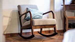A rocking chair with a cushion and a pillow, positioned against a wall with a tiled floor. - Hotel More Di Cuna (Monteroni d'Arbia)