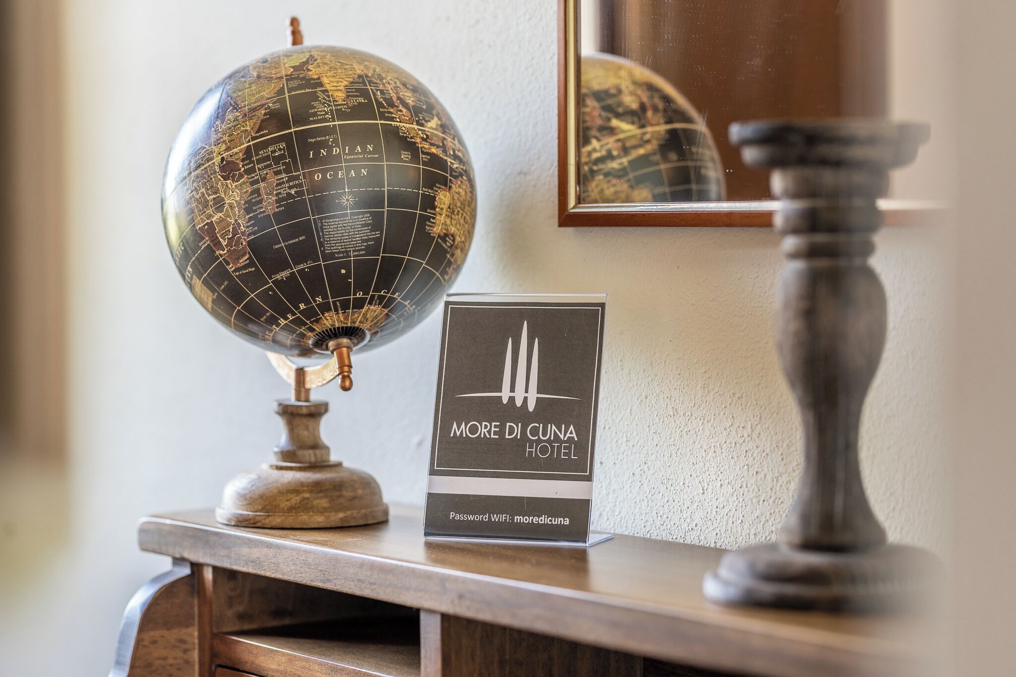 A globe, a framed sign for More Di Cuna Hotel, and a wooden stand.