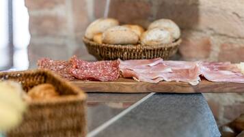 Une planche en bois garnie de différentes sortes de charcuteries et un panier de pain.