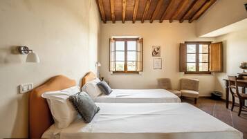 Una camera da letto con due letti, travi in legno, una scrivania e due finestre.