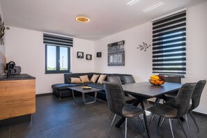 Un espace de vie moderne comprenant un coin cuisine, une table à manger avec des chaises, un canapé et une machine à café.