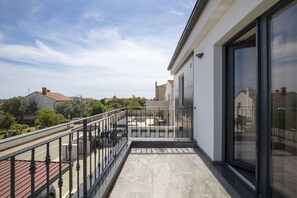 A balcony with a metal railing, a clear sky, and a view of surrounding buildings.