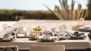 A table set for a meal with clear glassware, plates, and a vase with flowers. - Villa Pueblo (Nafplio)