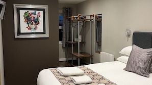 Habitación de hotel con cama, un cuadro en la pared, un armario y una lámpara en el techo.