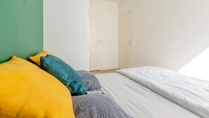 A bedroom with a bed, pillows, and a door in the background.