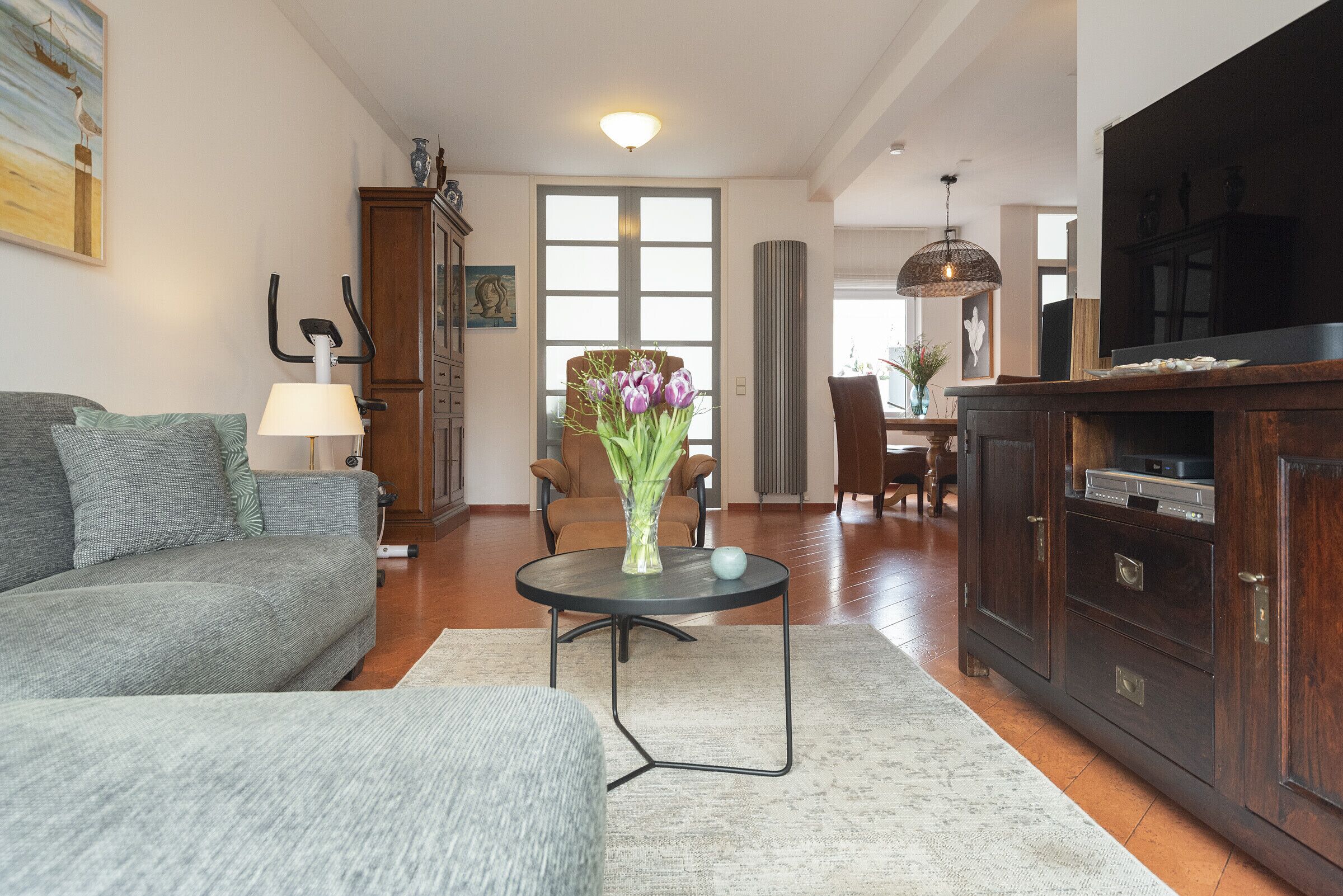 A living room with a sofa, a coffee table with a vase, a TV, and a cabinet.