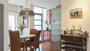 Una cocina moderna con un refrigerador de acero inoxidable, sillas de madera, una mesa de comedor y una bodega.
