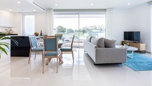 A modern living room with a sofa, chairs, a dining table, and a TV. - Adega Marina Apartments - Urban View (Lagos)