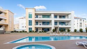 A modern building with a swimming pool, lounge chairs, and a well-maintained patio area. - Adega Marina Apartments - Urban View (Lagos)