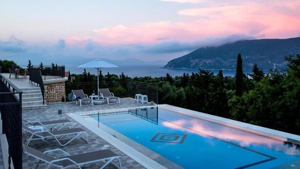 A pool area with lounge chairs and a view of the sea. - Villa Gionis (Evreti)