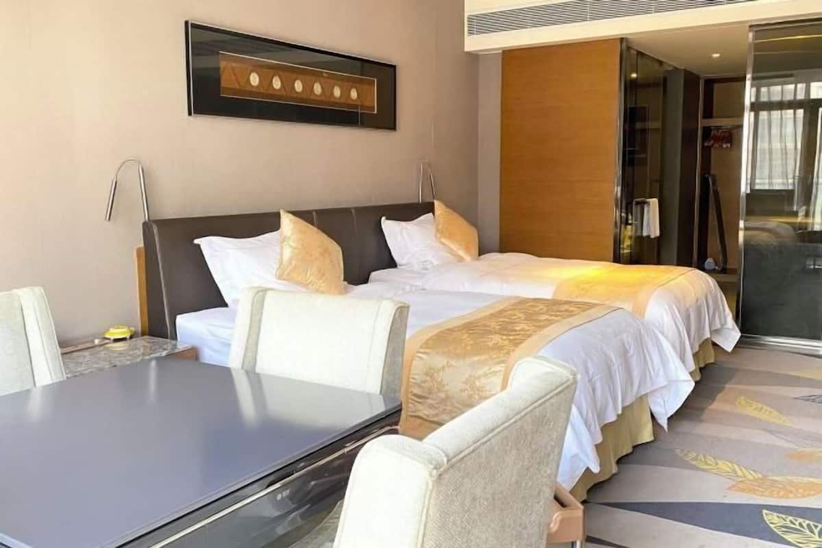 A hotel room with two beds, a desk, and a chair.