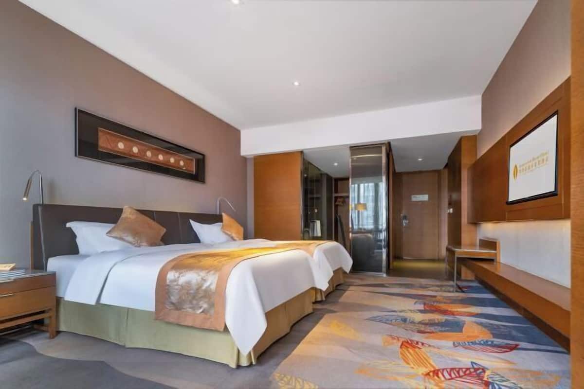 A hotel room with two beds, a large mirror, a wooden headboard, and a carpeted floor.